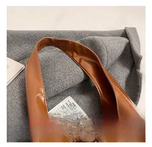 Detail of soft brown PU leather shoulder bag featuring a wide strap and knot decoration