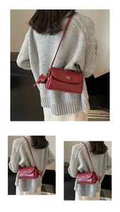 Détail du sac bandoulière en cuir bordeaux avec logo COIH ZDN et breloque éléphant