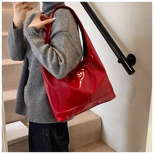 Detail of red glossy patent leather tote bag with drawstring bow on an indoor staircase