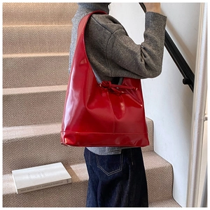 Chic glossy red hobo bag with drawstring detail shown in a stylish urban setting