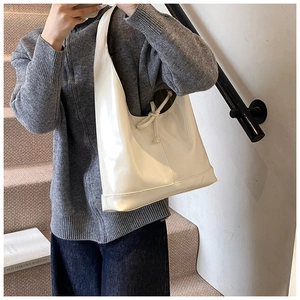 Close-up of creamy white glossy leather hobo bag featuring a decorative bow knot detail