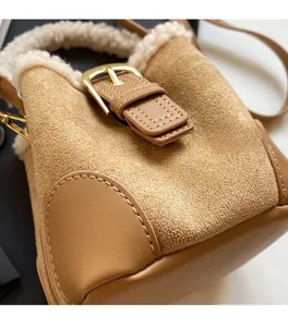 Detailed close-up of brown suede mini bucket bag with soft white faux fur trim and gold buckle