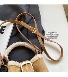 Detail of adjustable leather strap and lambskin trim on brown suede bucket bag