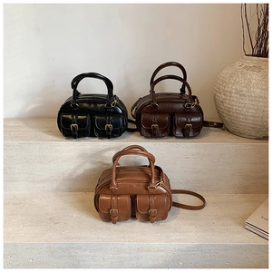Detailed shot of retro Boston bags in black and brown on minimalist stone steps