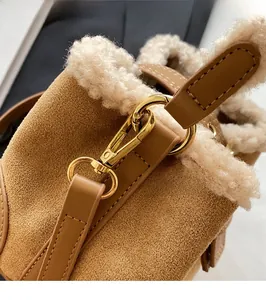 Detail of golden metal hooks and lamb wool trim on a brown suede bucket bag
