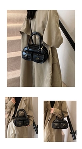 Detail of black bowling bag showing glossy texture and two decorative buckle pockets