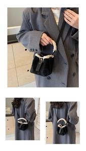 Detail of mini black bucket bag with plush white trim and suede texture for autumn