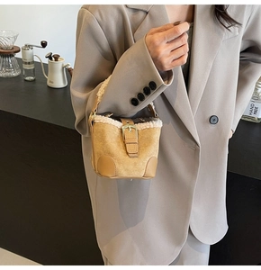 Close-up of suede bucket bag with white faux fur trim and gold buckle detail