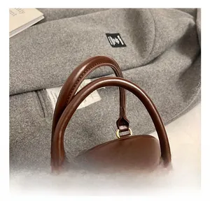 Detail view of smooth dual handles on a vintage brown leather bowling handbag