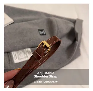 Detail of brown leather adjustable strap with gold buckle and white contrast stitching