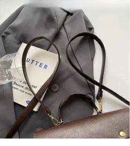 Detail of dark brown leather bag with golden magnetic snap and dual strap system