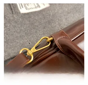 Detailed close-up of the vintage brown leather bag with golden metal strap hooks