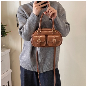 Close-up of retro brown bowling bag featuring twin front pockets and gold buckle details