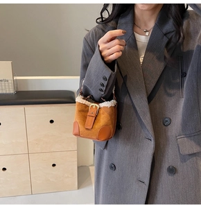 Close-up of brown suede mini bucket bag with soft faux fur trim and gold metal buckle