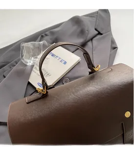 Close-up of deep brown pebbled leather handbag handle with gold metal hardware details