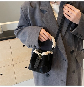 Detail of mini black bucket bag with white faux fur trim and adjustable crossbody strap