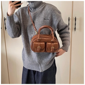Detail of vintage brown PU leather handbag featuring dual front pockets and gold buckles