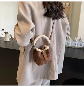 Detail view of retro suede bucket bag with white fleece trim and metal buckle on strap