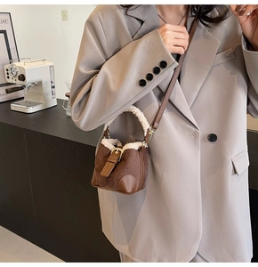 Detail of a brown suede mini bucket bag with soft white shearling trim and gold buckle