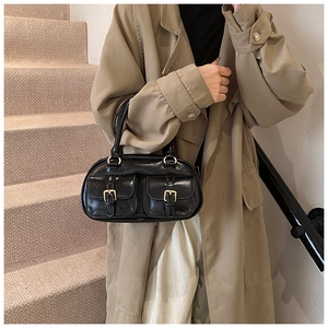 Detail shot of black leather handbag with two small buckle pockets and gold hardware