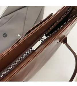Gros plan sur la fermeture éclair en métal et la texture du cuir marron du sac à main