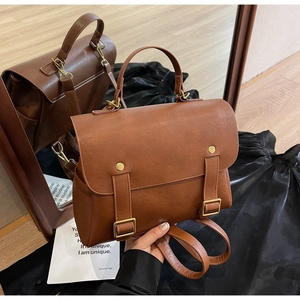 Detail of vintage caramel brown PU leather backpack with gold buckles and top handle