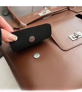 Détail du fermoir rotatif en métal argenté et de la boucle sur un sac en cuir marron