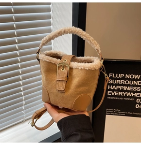 Close-up of brown suede bucket bag featuring creamy white faux fur trim and gold buckle detail