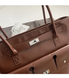 Détail d'un sac à main en cuir marron avec fermoir métallique et surpiqûres fines