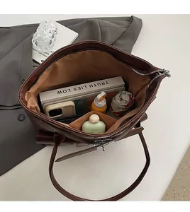 Vue détaillée du grand compartiment intérieur du sac cabas marron avec divers objets