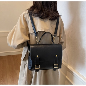 Detail of vintage black leather backpack with gold hardware and flap cover design