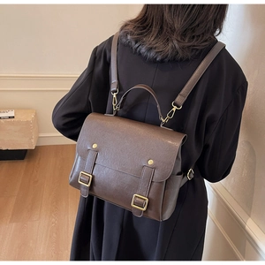 Brown vintage faux leather backpack shown on a model, featuring gold buckles and a top handle