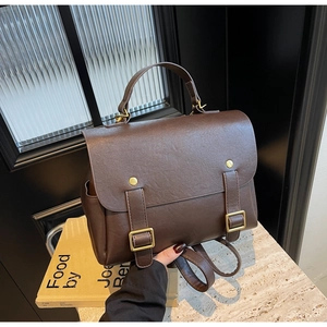 Detail of dark brown vintage PU leather backpack showing top handle and golden buckles