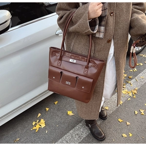 Détail d'un sac cabas en cuir marron avec fermoirs métalliques et poches à rabat