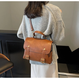 Detail of vintage brown leather messenger bag with gold metal buckles and adjustable strap