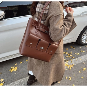 Détail d'un grand sac cabas en cuir marron avec poche à rabat et fermoir argenté dans la rue