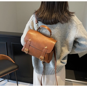 Detail of vintage caramel leather backpack featuring brass buckles and top handle texture
