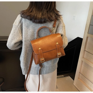 Rear view of model wearing a vintage brown leather backpack with gold buckle detail