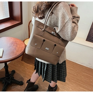 Détail d'un cabas en cuir marron avec fermoir rotatif et poches avant utilitaires