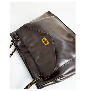 Detail of vintage brown shoulder bag with golden metal turn-lock and chain strap texture