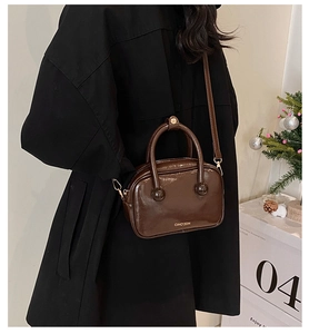 Dettaglio di una borsa a mano in pelle lucida marrone con hardware dorato e logo CIHO'2DN