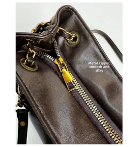 Detailed macro shot of the smooth gold metal hardware zipper on brown leather tote bag