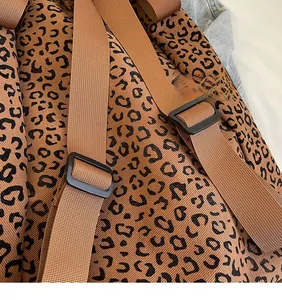 Macro detail of leopard print canvas backpack with adjustable brown woven shoulder strap
