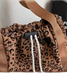 Detail of leopard print tote bag with drawstring closure and woven rope handles