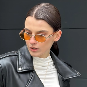 Retro oval metal sunglasses with orange lenses shown on a model wearing black leather