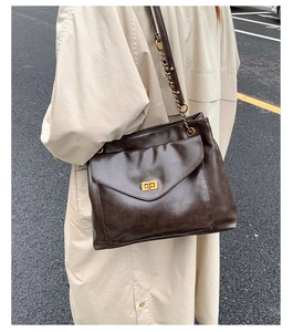 Close-up of brown vintage PU leather tote with gold twist lock and chain strap detail
