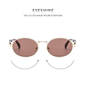 Detailed macro view of vintage oval sunglasses with gold metal frame and brown lenses