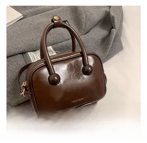 Dettaglio della borsa in pelle verniciata marrone scuro con manico a sfera unico