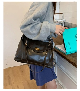 Detail of dark brown leather tote bag with a vintage gold twist lock and shoulder strap