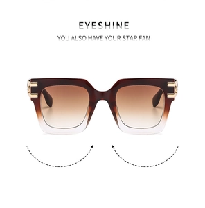 Detail of square oversized sunglasses with brown gradient frames and gold metal accents